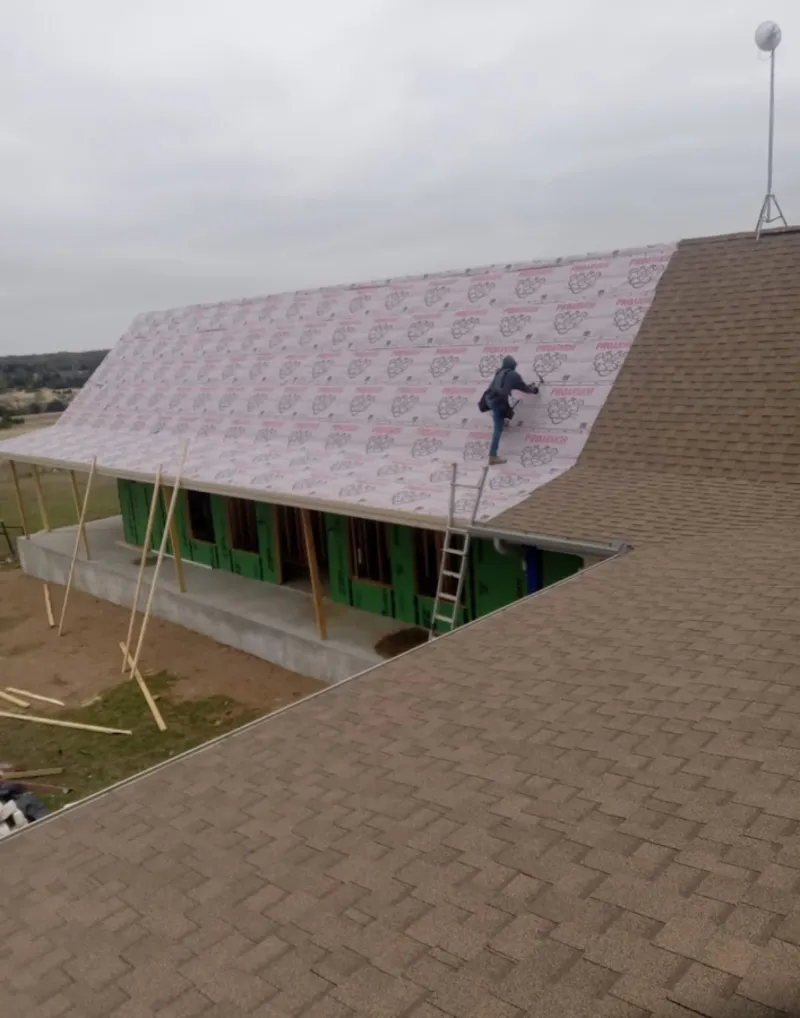 Worker preparing underlayment for a metal roof installation in Indianapolis